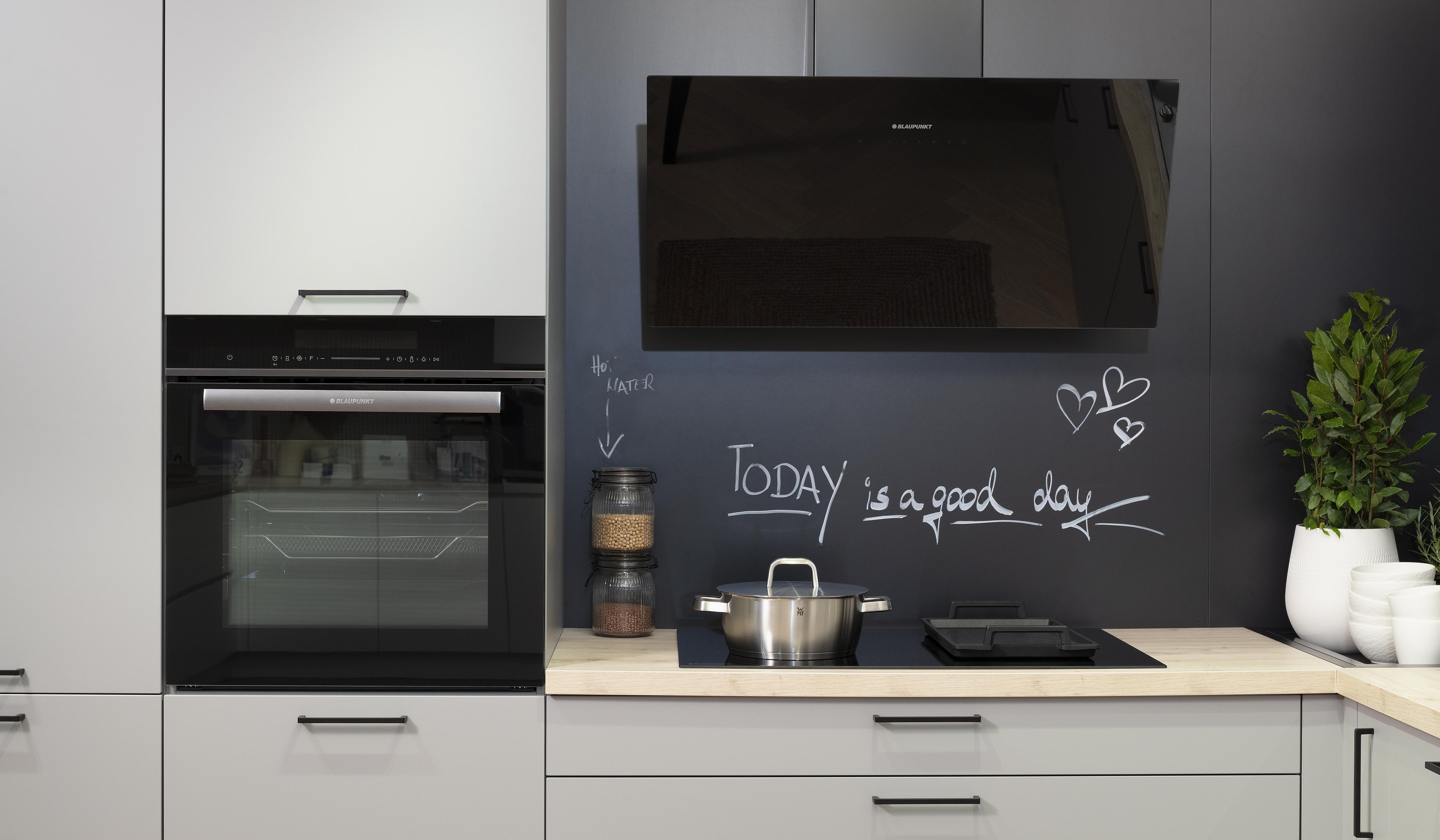 Häcker-Küche in Perlgrau mit Kochfeld, Backofen und Kopffreihaube von Blaupunkt. 